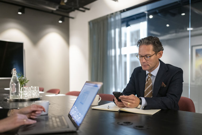 Mann sitter på telefonen i et møterom